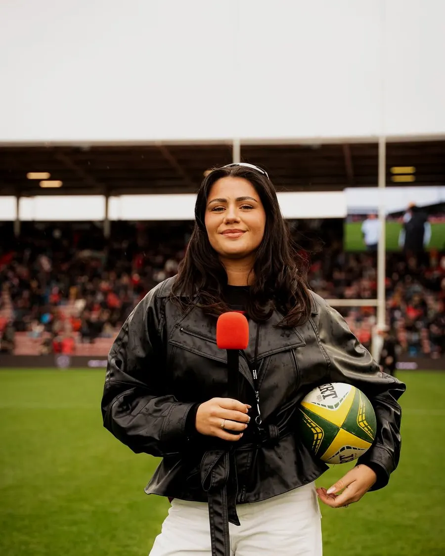 Rose Thr, micro en main au bord d'un terrain de rugby